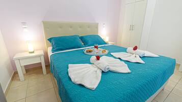 Una cama bien hecha con una colcha color aguamarina, almohadas blancas y toallas dispuestas sobre la cama.