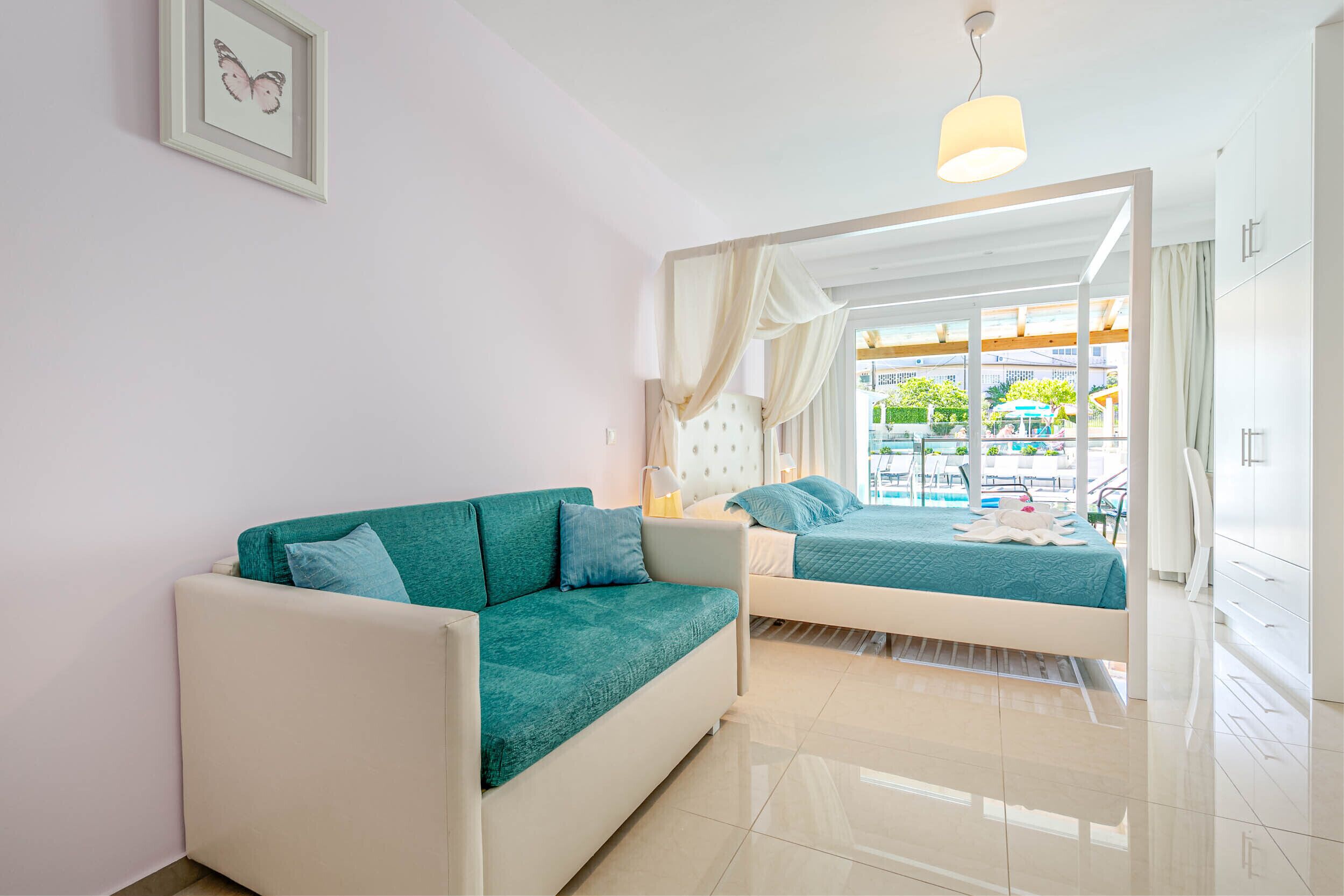Habitación de hotel moderna con sofá, cama y vista al área de piscina al aire libre.