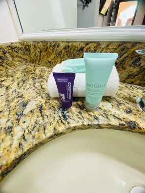 A bathroom countertop with a granite surface, a white towel, and two toiletry bottles.