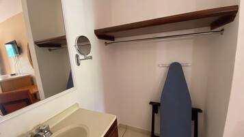 Une salle de bain avec un lavabo, un miroir et une planche à repasser bleue.