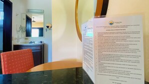 A hotel reception desk with a large mirror, a red chair, and a sign detailing hotel regulations.