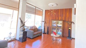 A spacious living area with a sofa, a small table, and a decorative bird statue. - Hotel Flamingos (Guadalajara)