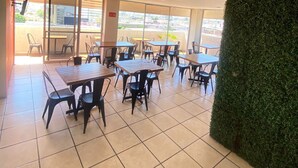 An indoor dining area with tiled flooring, multiple tables and chairs, and a view through large windows. - Hotel Flamingos (Guadalajara)