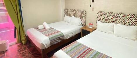 A hotel room with two beds, a nightstand, and a wall-mounted lamp.