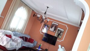 A bedroom with a bed, a television mounted on the wall, and a chandelier. - Freedom House (Addis Ababa)