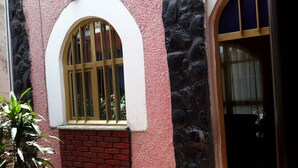 A building with a red brick base, a pink textured wall, and a window with vertical bars. - Freedom House (Addis Ababa)