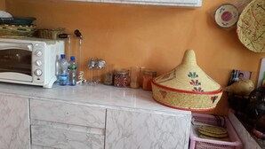 A kitchen counter with a microwave, water bottles, glass jars, and a woven container. - Freedom House (Addis Ababa)