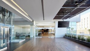 Un vaste espace intérieur doté d’un plancher en bois, de rampes en verre et d’un grand téléviseur à écran plat fixé au mur.