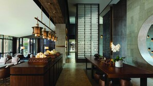 Una hall moderna di un albergo con un bar centrale, zona salotto e una parete decorativa.