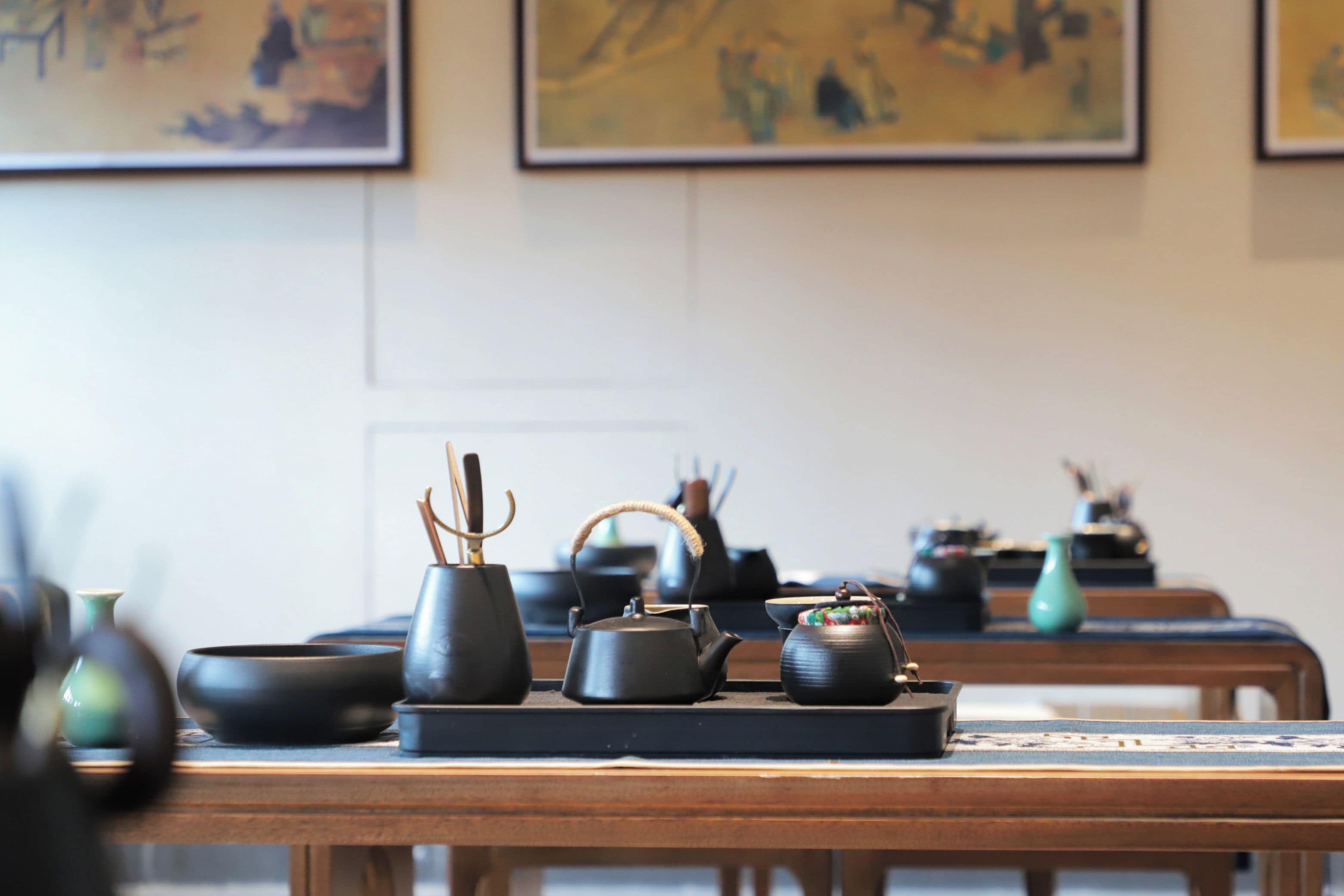 Una mesa con varios juegos de té y una tetera.