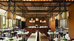 A spacious restaurant with high ceilings, hanging pendant lights, and a central buffet area. - JW Marriott Hotel Qufu (Jining)