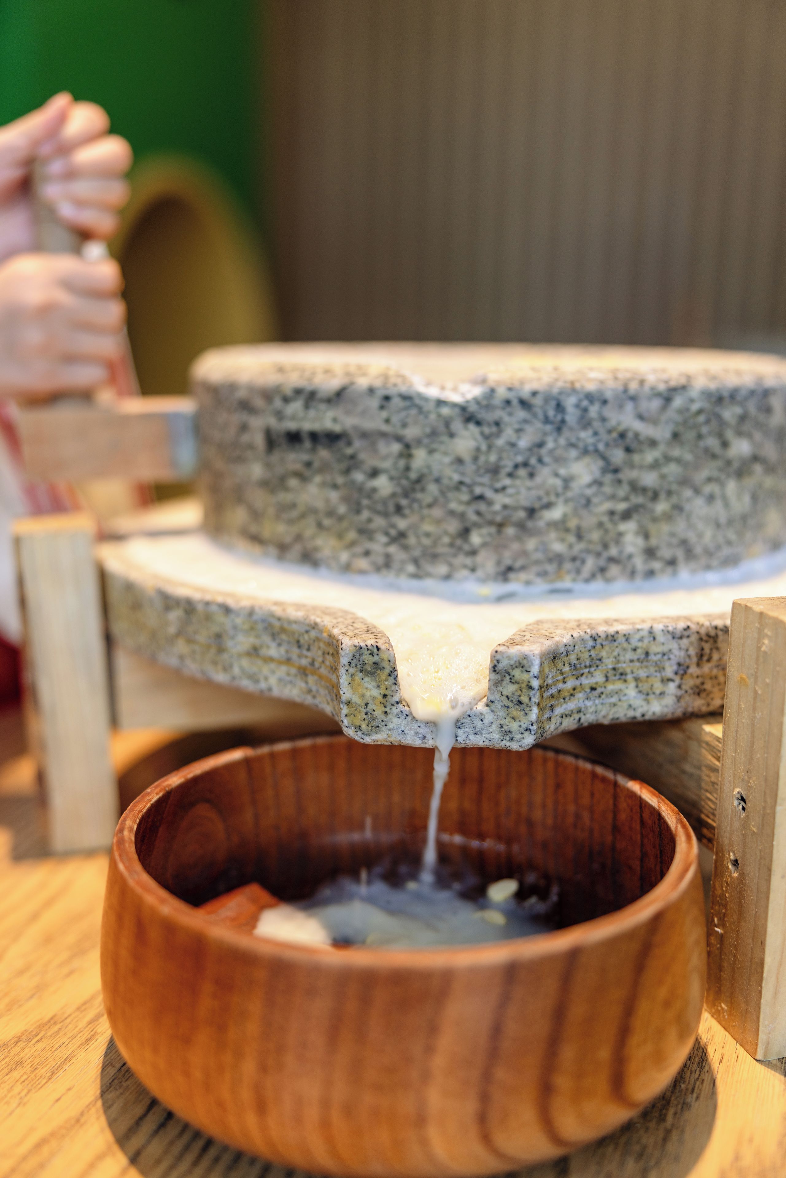 A wooden bowl with a liquid being poured into it.