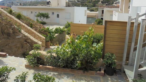 Zona residencial amb cases adossades, un mur de pedra de contenció i un jardí amb plantes en testos.