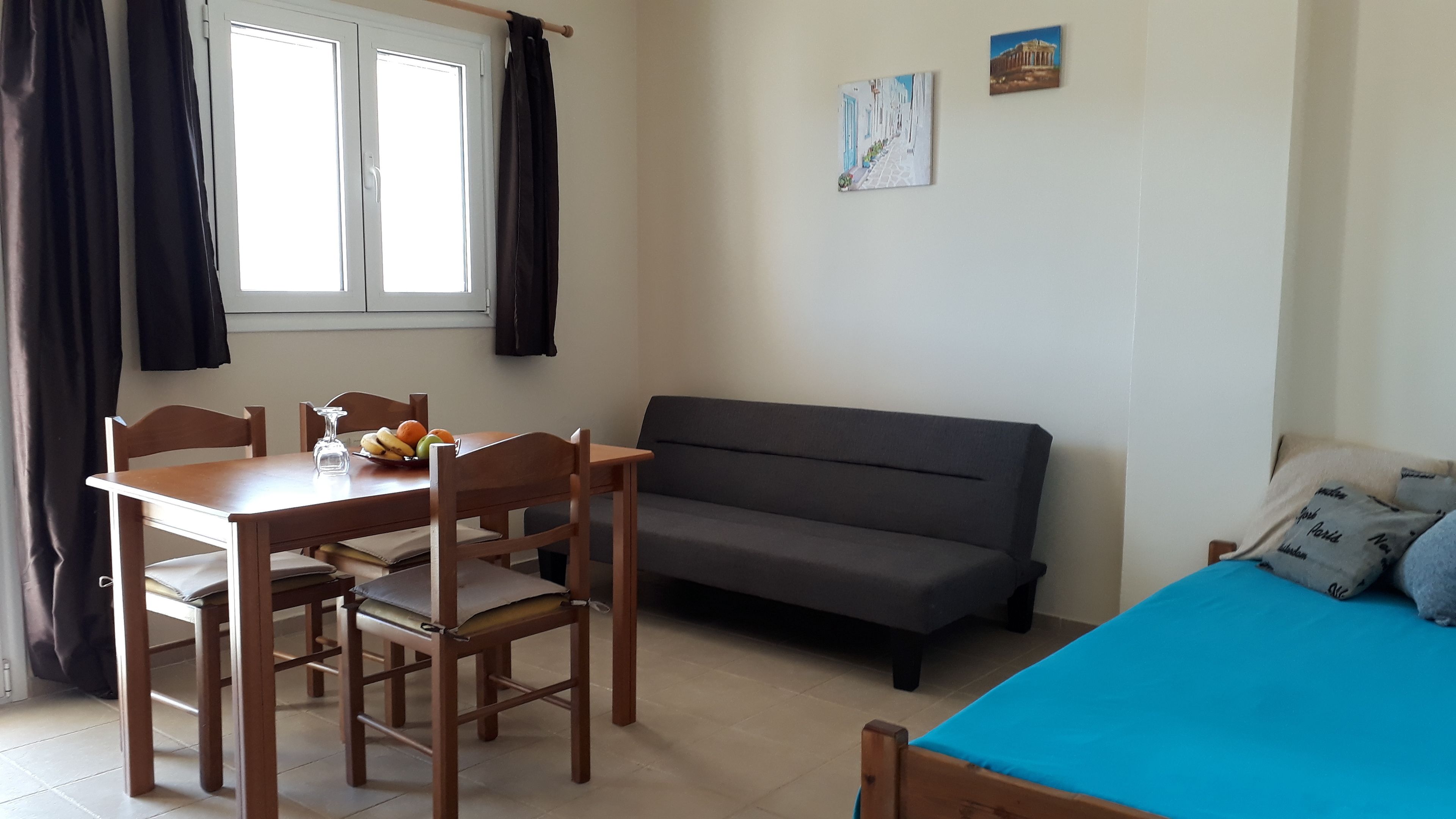 A room with a dining table, chairs, a sofa, and a bed.