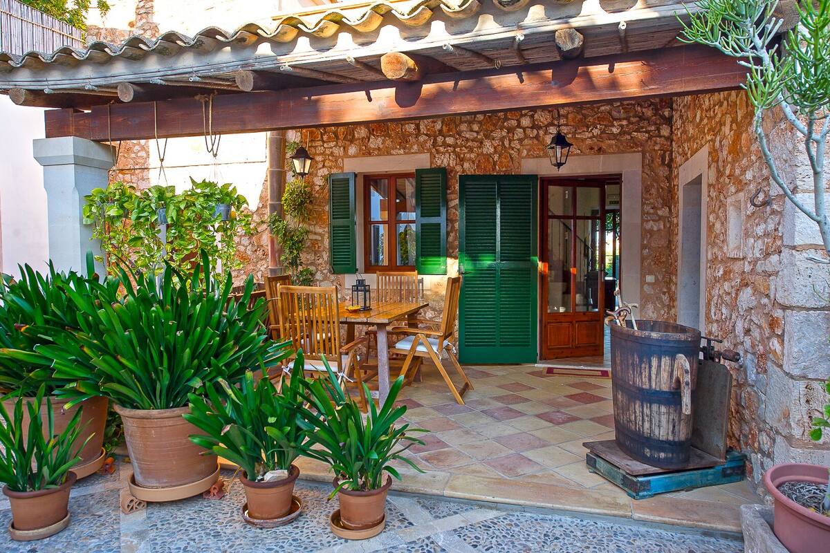 A rustic outdoor seating area with a stone wall, wooden furniture, and potted plants.