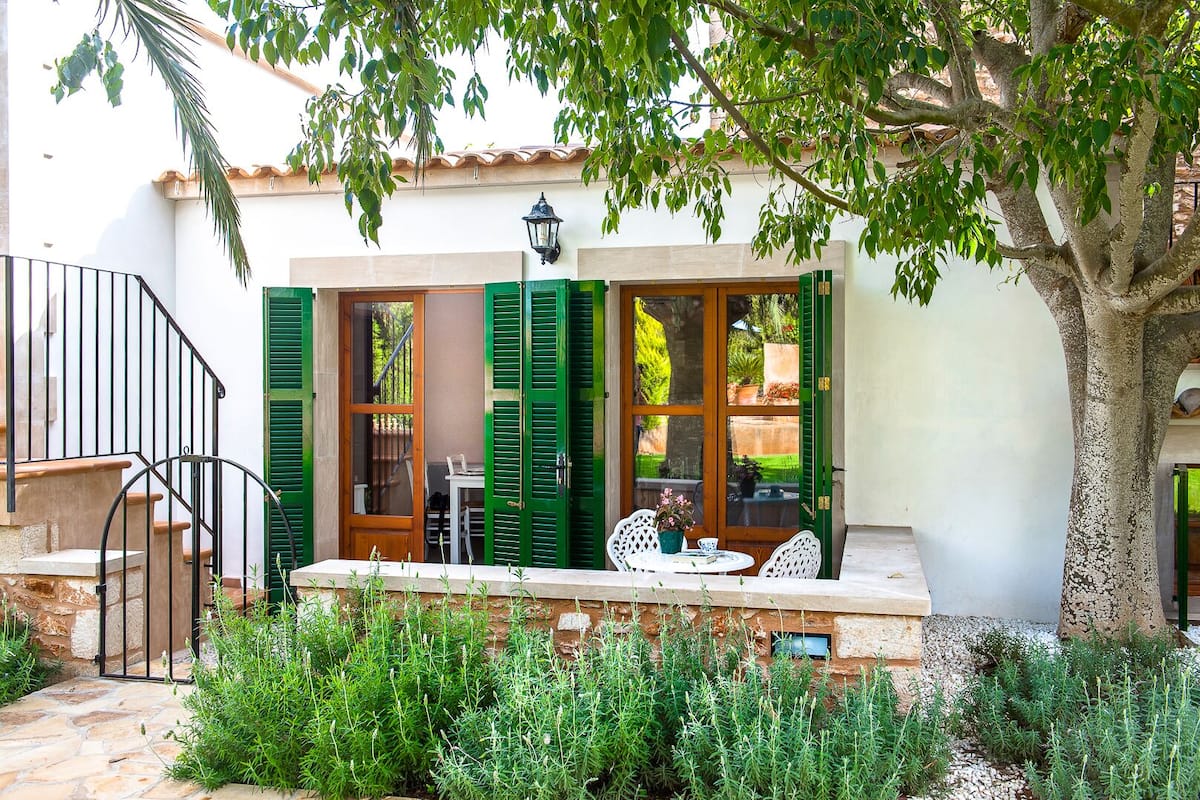 A patio with a table and chairs, a wooden door, and a stone wall.