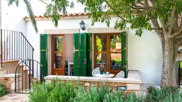 A patio with a table and chairs, a wooden door, and a stone wall.