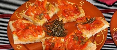 A plate of bruschetta with tomato and basil on a striped tablecloth.