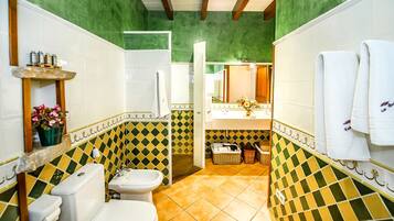 A bathroom with a toilet, sink, and shower area, featuring green and yellow patterned tiles.