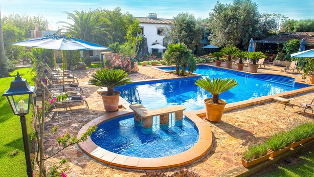 Una piscina con una sección circular, rodeada de plantas en macetas y mobiliario exterior.