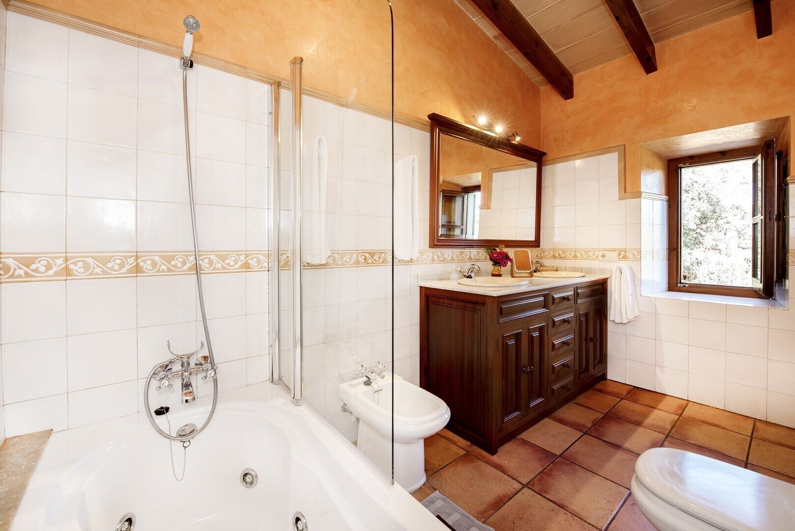 Un baño con bañera, ducha, inodoro y tocador con espejo.