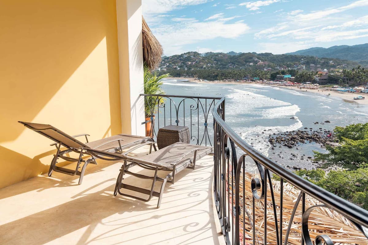 A balcony with a view of a beach and mountains.