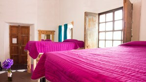 A room with two beds, wooden doors, a window, and a mirror.