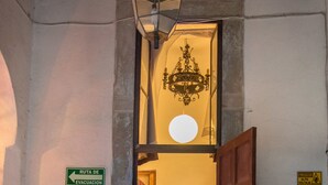 A hotel entrance with a sign indicating an evacuation route, a first aid symbol, a chandelier, and a checkered floor pattern.