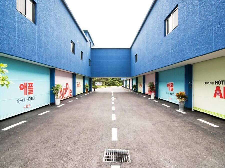 A drive-in hotel with a central courtyard, potted plants, and signage in a foreign language.