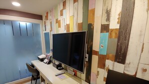 A hotel room with a desk, a computer, a television, and a chair. - Apple Drive-in Motel (Yeoju)