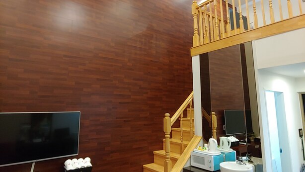 A modern interior with a wooden staircase, a flat-screen TV, a coffee machine, and a sink. - Apple Drive-in Motel (Yeoju)