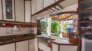 Eine Küche mit weißen Schränken, einer Granit Arbeitsplatte, einem Spülbecken und einem Fenster mit Blick auf einen Garten.
