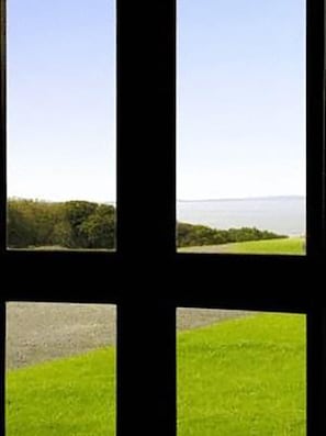 A view through a window with a grassy field and a distant landscape. - Ballinalacken castle country house hotel (Lisdoonvarna)