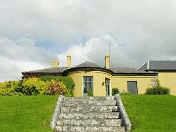 A two-story building with a curved roof, a front door, and a staircase leading to the entrance. - Ballinalacken castle country house hotel (Lisdoonvarna)