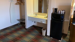 A hotel bathroom with a sink, mirror, towel rack, and a coffee machine.