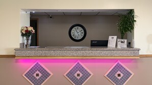A reception desk with a clock, a sign for service requests, and a plant.