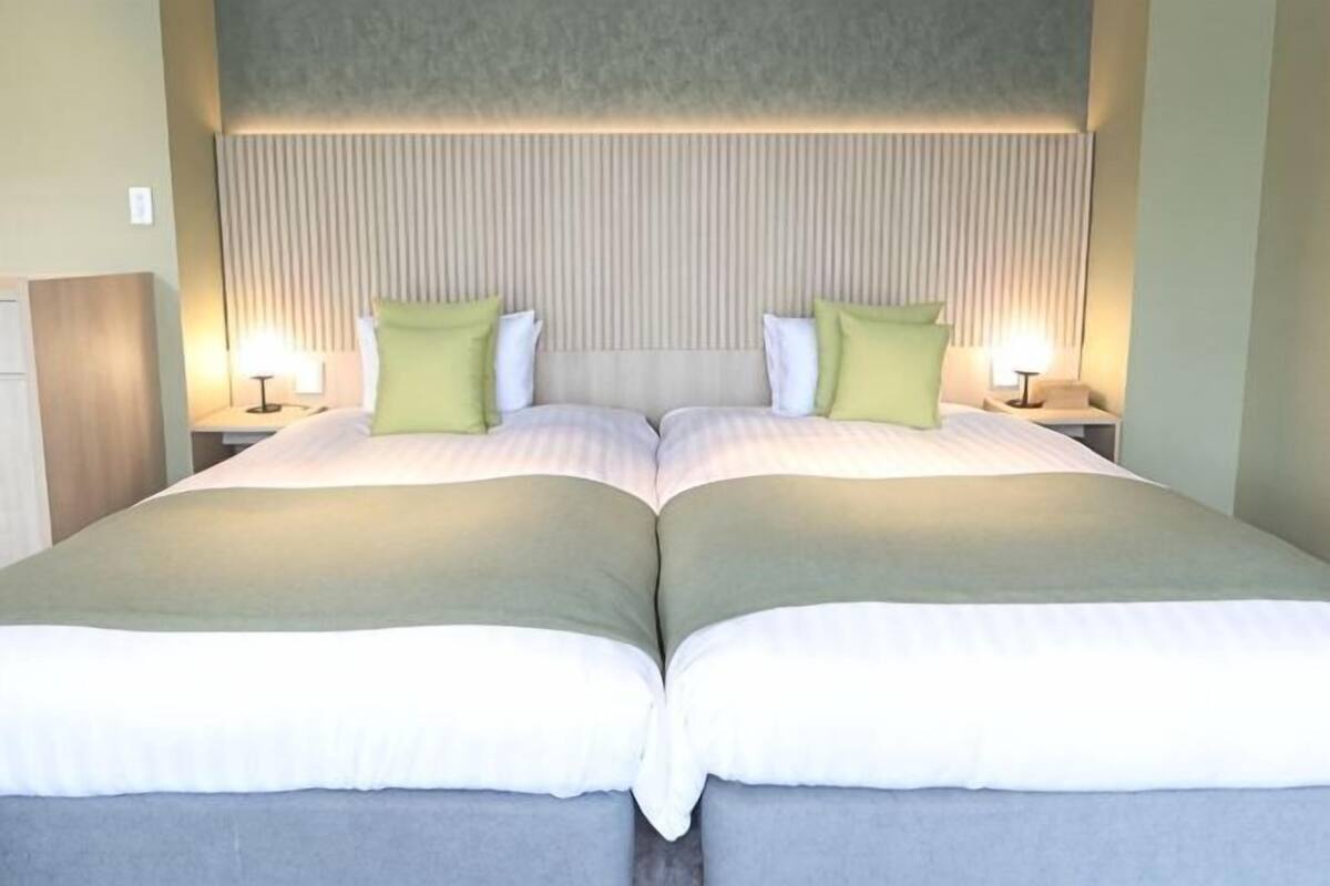 A double bed with two nightstands, each with a lamp, in a hotel room.