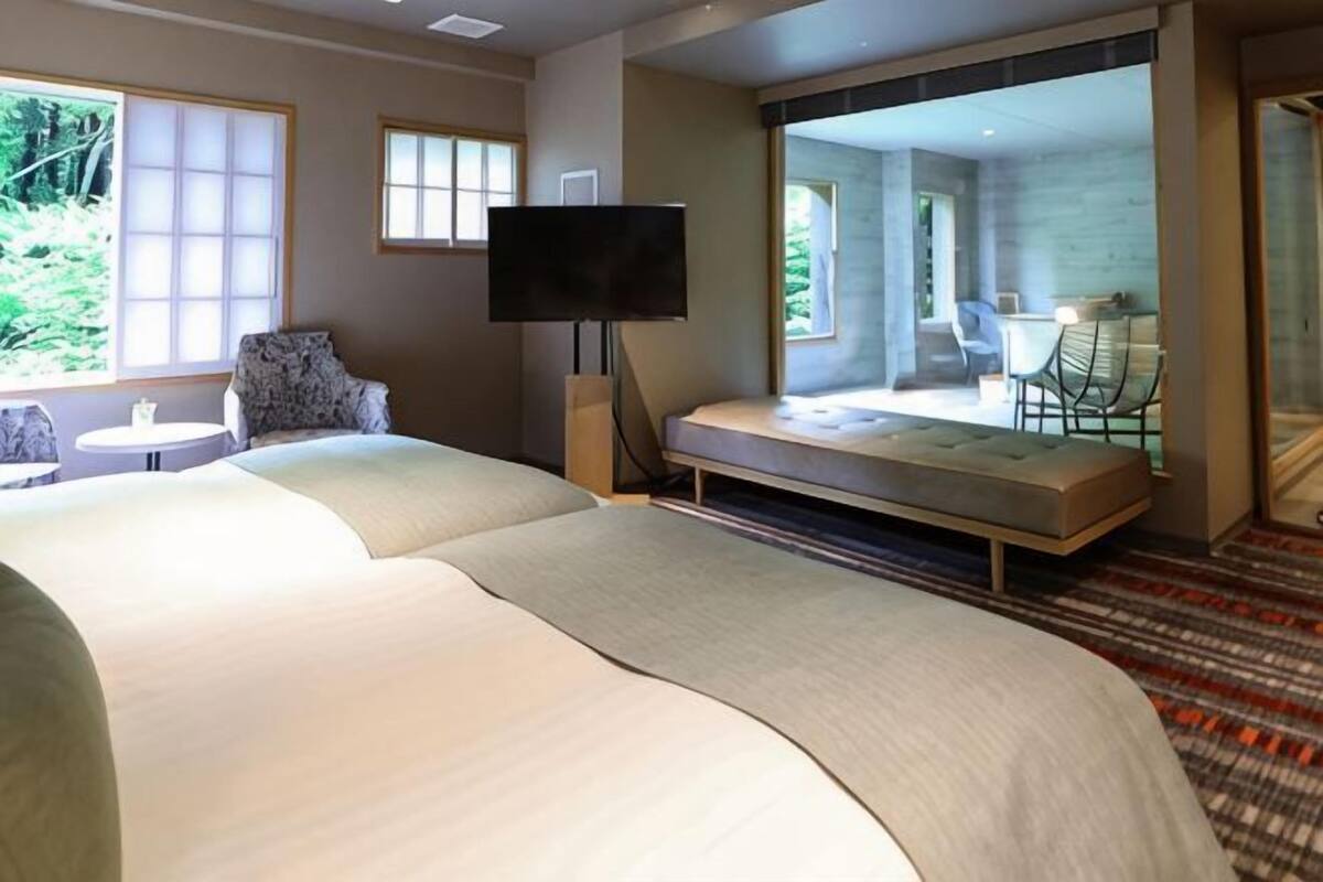 A hotel room with a large bed, a television, a seating area with a table and chairs, and a view of the outdoors.