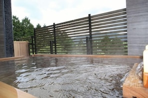 A hot tub with water, a wooden deck, and a metal fence. - HAKONE YUYADO ZEN (Hakone)