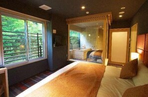 A bedroom with a large bed, a desk, and a view of greenery through the window. - HAKONE YUYADO ZEN (Hakone)