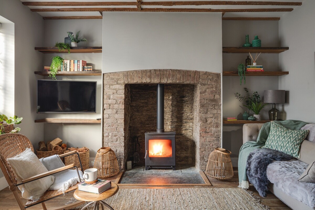 Una sala acogedora con chimenea, estanterías de madera, televisor y asientos cómodos.