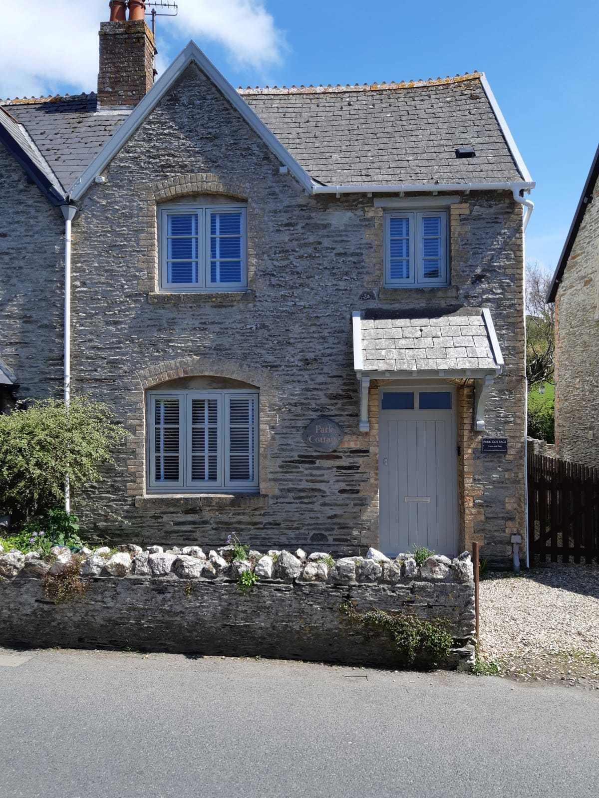 A stone cottage with a gabled roof, a central entrance, and a small porch.