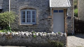 A stone cottage with a gabled roof, a central entrance, and a small porch. - Seascape Hideaways at Mortehoe (Woolacombe)