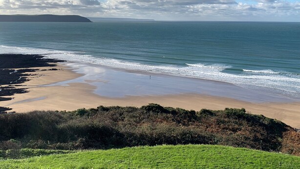 A coastal landscape with a sandy beach, calm sea, and a distant landmass. - Seascape Hideaways at Mortehoe (Woolacombe)
