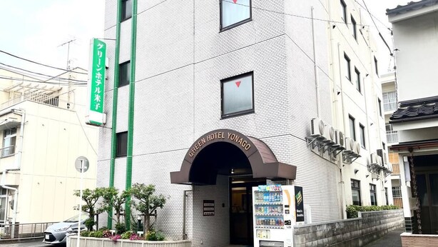 Un edificio con un cartello che riporta 'Green Hotel Yonago' e una macchina distributrice all'esterno.
