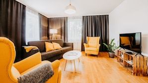 A modern living room with a sofa, armchair, coffee table, and TV stand. - Landgut Riegerbauer (Feistritztal)