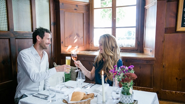 A couple dining at a table with a candle, wine glasses, and a basket of bread. - Landgut Riegerbauer (Feistritztal)