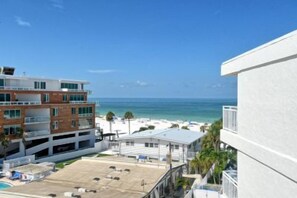 A beachfront hotel with multiple floors, a parking area, and a view of the ocean.