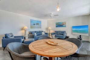 A room with a round wooden table, blue sofas, and two paintings on the walls. - Luxury Gulf-Side Retreat | Remodeled 2-Bedroom Condo | Siesta Key (Sarasota)