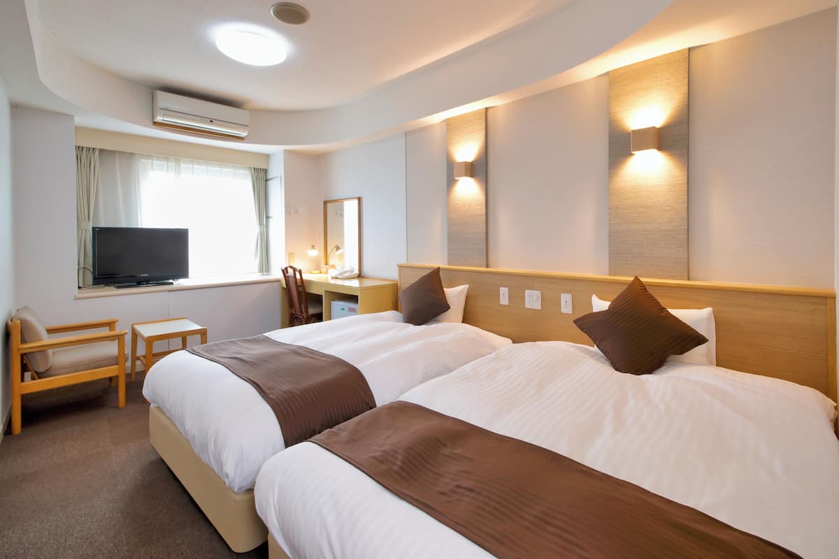 Une chambre d’hôtel avec deux lits, une télévision, un bureau et une chaise.